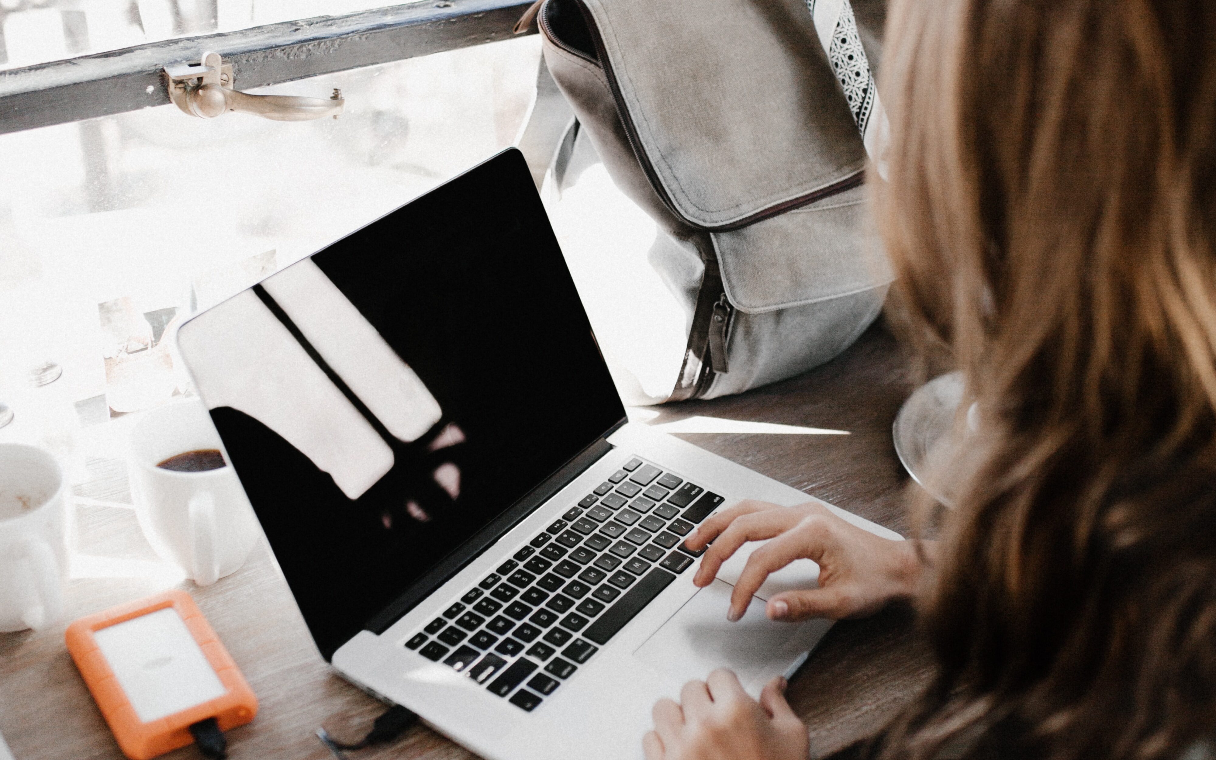 laptop on wooden table and woman typing