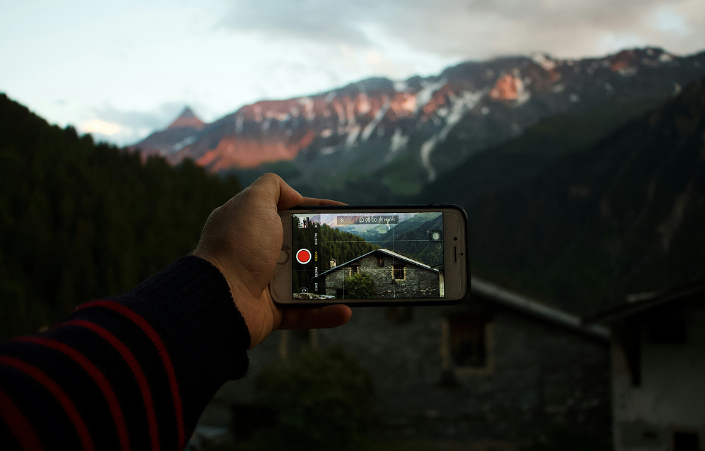 iPhone taking video of building in front of a mountain landscape