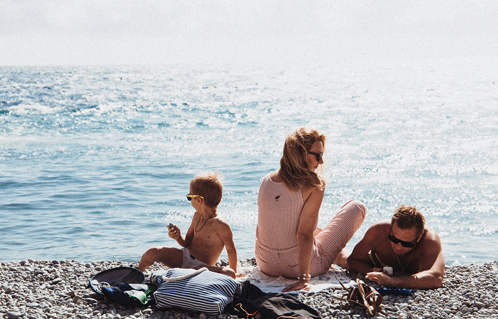 A happy family sits on a beach blanket, laughing and soaking up the sun by the ocean