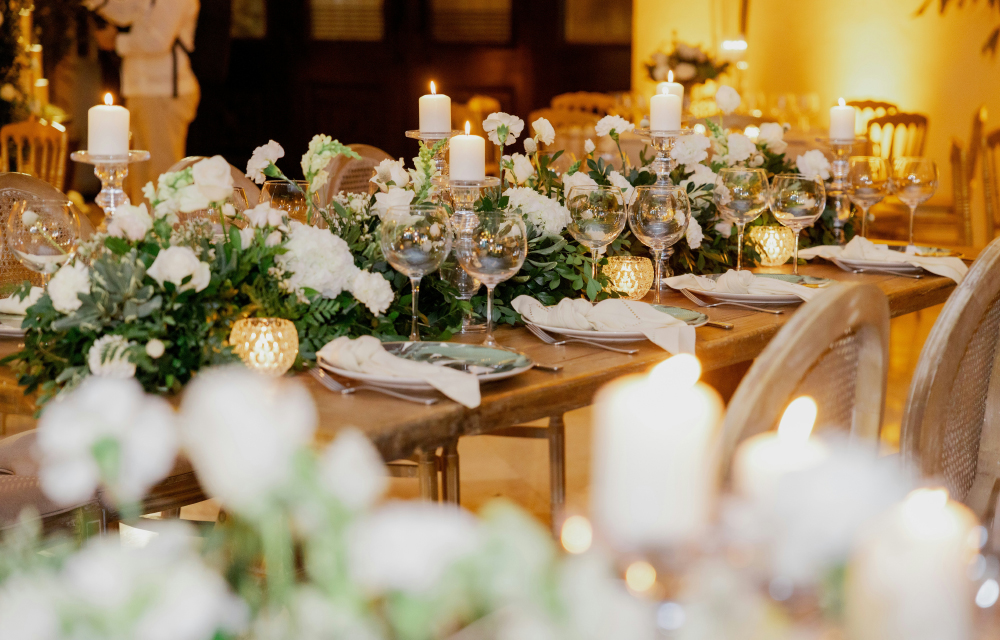 A beautiful wedding table set-up decorated with matching white flowers, candles and silverware.