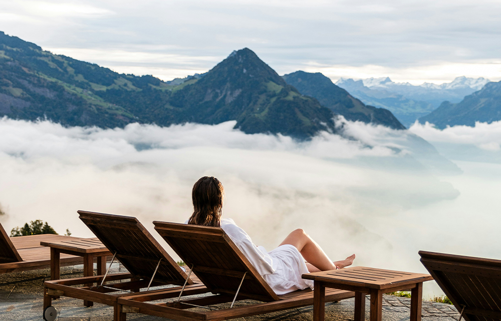 A woman lounging in front of an overlooking view of a foggy mountain