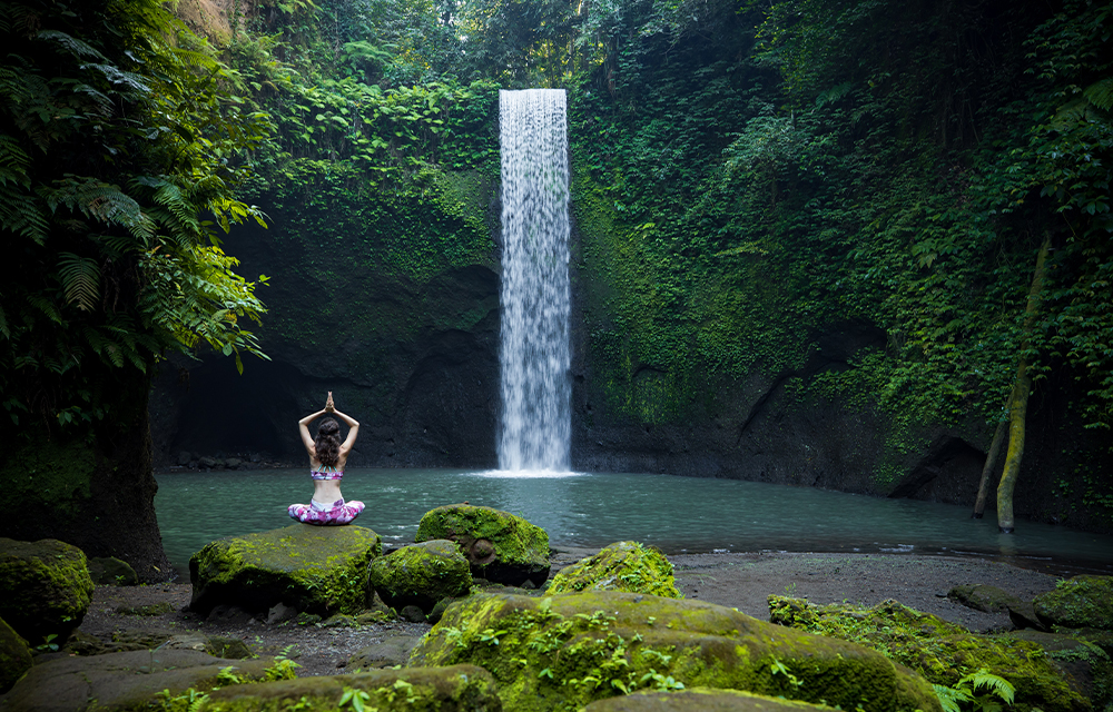 woman doing yoga in front of a waterfall